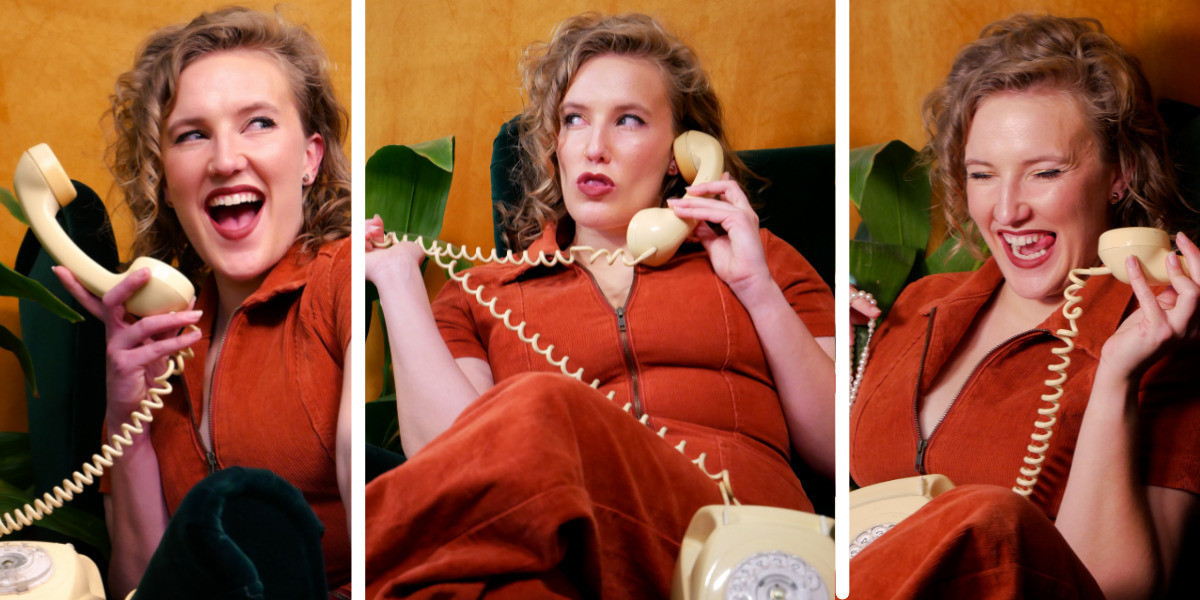 A triptych of 3 images side by side, split up by white lines. In all 3 photos Mim is wearing an orange jumpsuit, holding a retro phone, and sitting on a dark green armchair in front of a mustard background and beside a leafy indoor plant. In the first photos from the left she is holding the receiver away from her ear and looking up excitedly, a wide smile on her face. In the middle photo she is sitting cross-legged on the armchair, sucking her teeth and looking off to the left of frame with an expression that looks malicious. She is holding the phone receiver in her left hand and pulling the curly cord of the phone across her body with her right hand.  In the far right photo she is holding the receiver to her ear and laughing with her eyes closed.