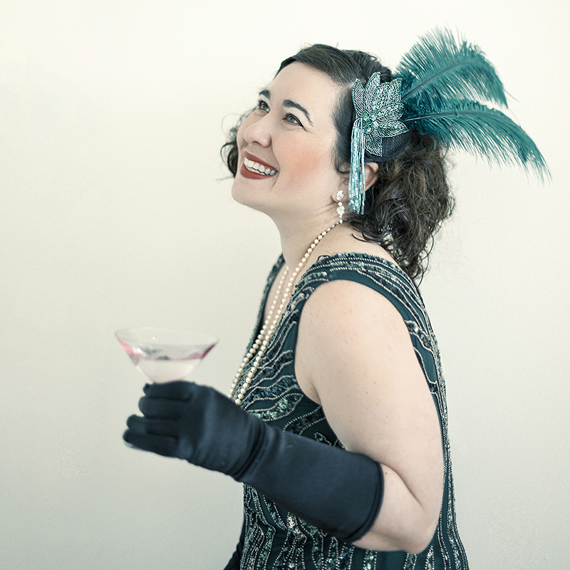 A young woman dressed as a flapper, enjoying a vintage cocktail.