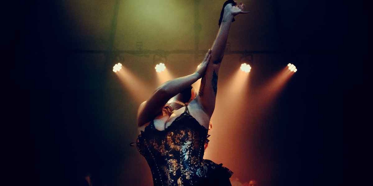 Fafi D'Alour onstage wearing blue corset pulling off black glove