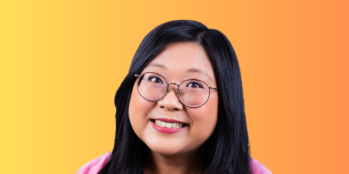The Sweet and Sour Hour of Power - Smiling Chinese woman wearing glasses, in front of an orange background.