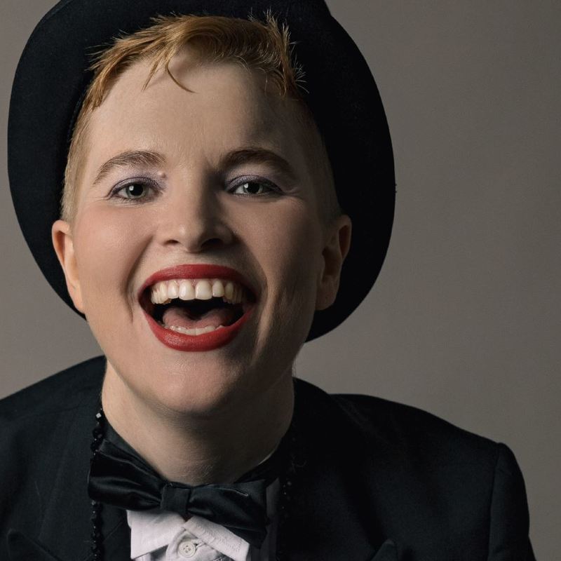 a performer, dressed in a top hat, laughing.