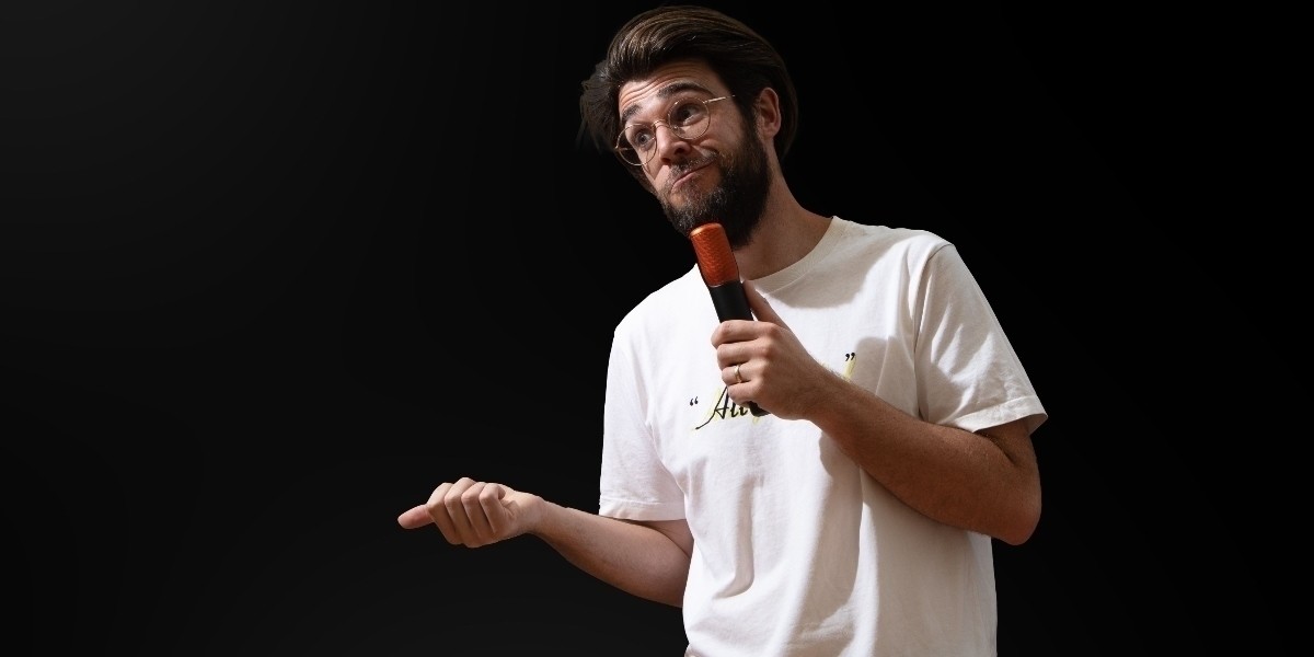 Tom W Clarke performing stand up comedy on a black background