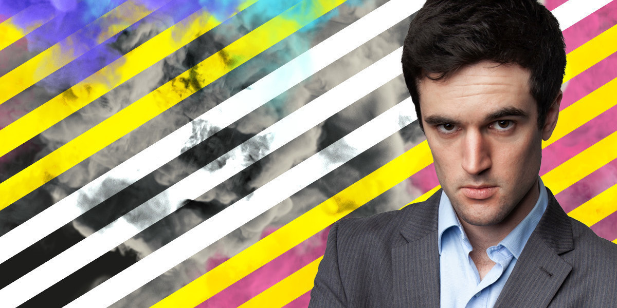 Image of a white man in a suit looking up at the camera. He is in front of a background inspired by the publicity images of the film 24 Hour Party People.