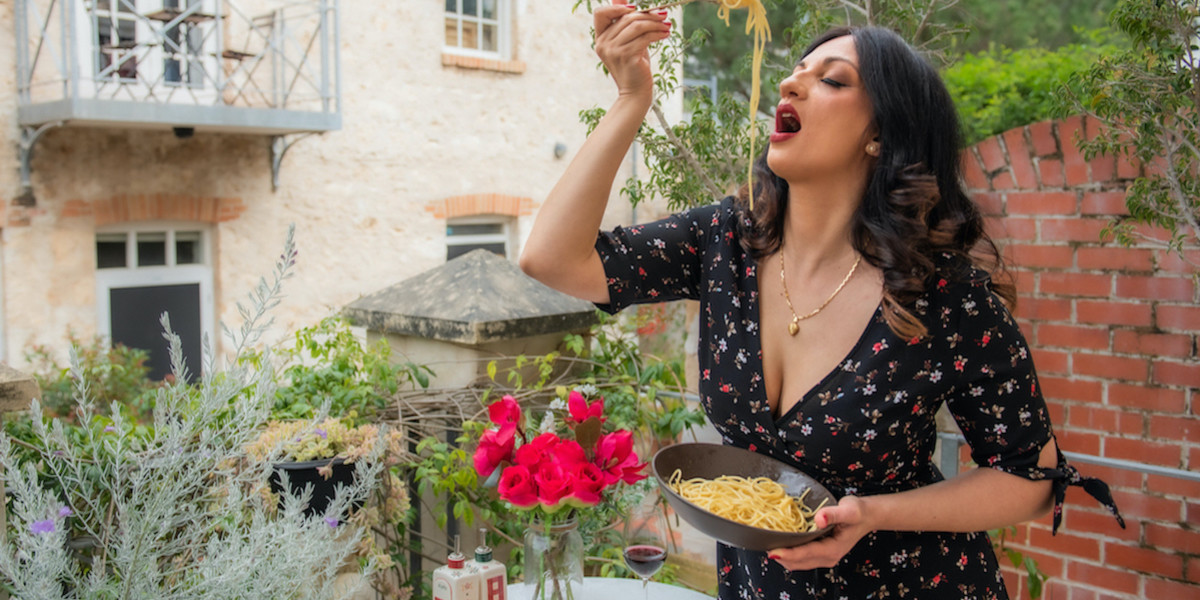 Buona Sera Signorina - Italian Music Meets Jazz - A woman is eating spaghetti surrounded by a typical Italian landscape.