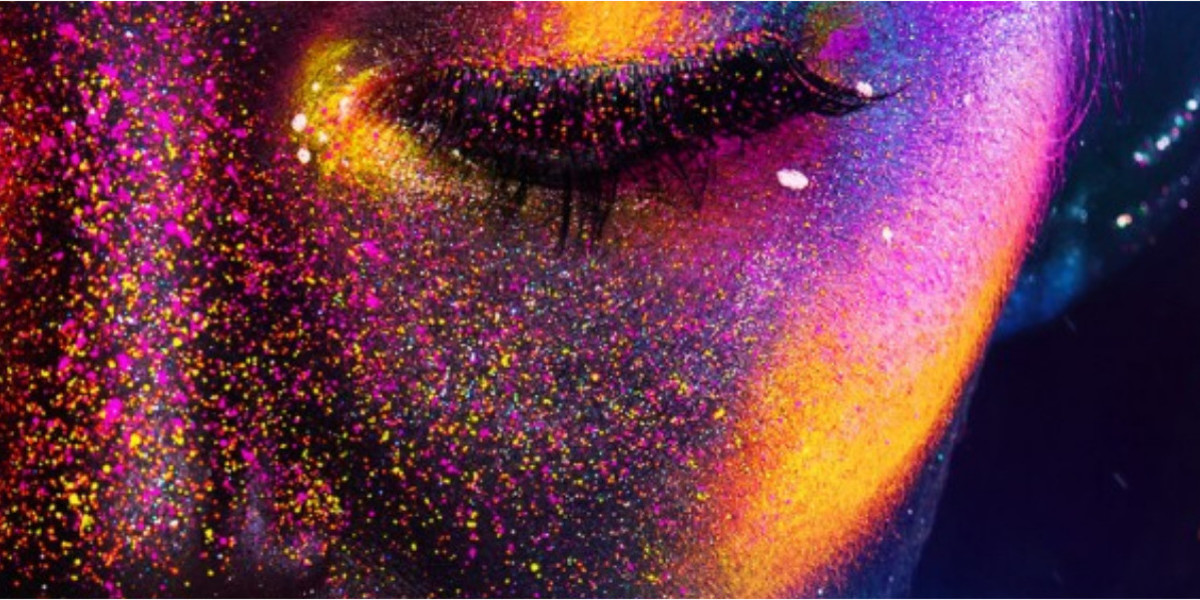A woman's face is coloured with splatters of brightly coloured Ultra Violet paint