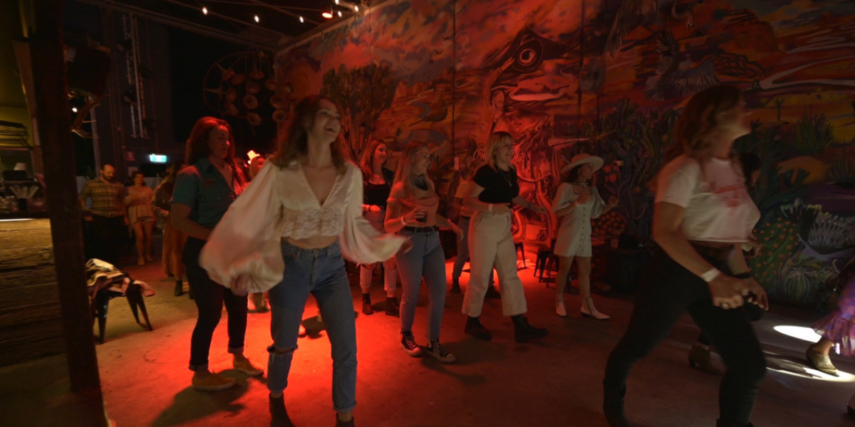 People line dancing and laughing in a bar.