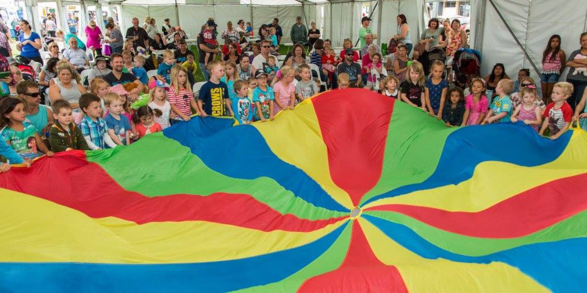 Children are holding onto a giant parachute ready to play some games
