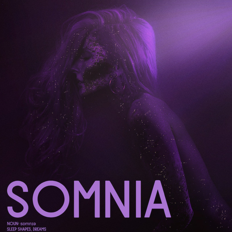 SOMNIA 2.022 - A single female kneels with her eyes closed, as if in a trance. Moonlight shines over her shoulder, illuminating star dust all over her face, long flowing hair & body.