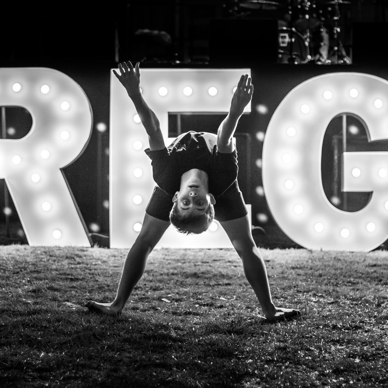Lime-Light - A boy doing a back bend in front of a sign with large letters R E N light up by bright lights