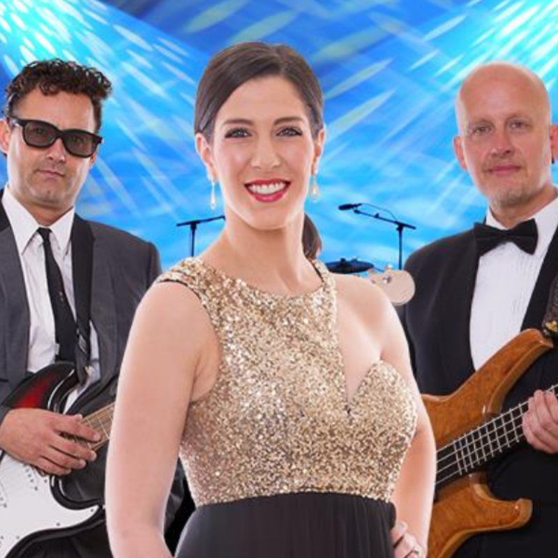 Tony holds a guitar, Dani is wearing a sparkly dress and Nige holds his bass guitar