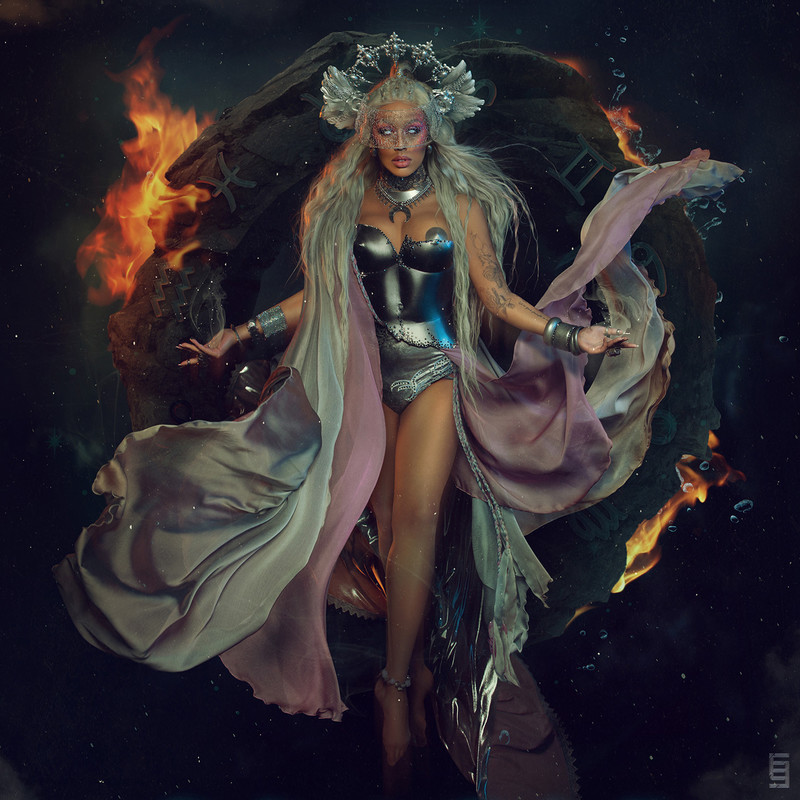 The Oracle floating in space, with white eyes, arms wide open and her long silver hair flying around her. She is wearing a silver headpiece and chest plate armour with floaty silver and purple fabric surrounding her. Behind her is a rock formation  engulfed in fire, water splashes and smoke with the zodiac signs carved into it.