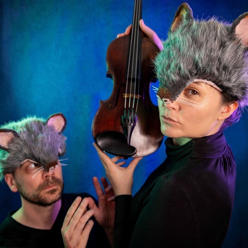 A man in an animal hat and a woman in an animal hat holding a violin
