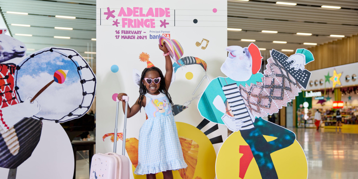 Young girl, wearing a blue Cinderella dress holding her hat in one hand and suitcase in the other is standing in front of cutouts of colour animals