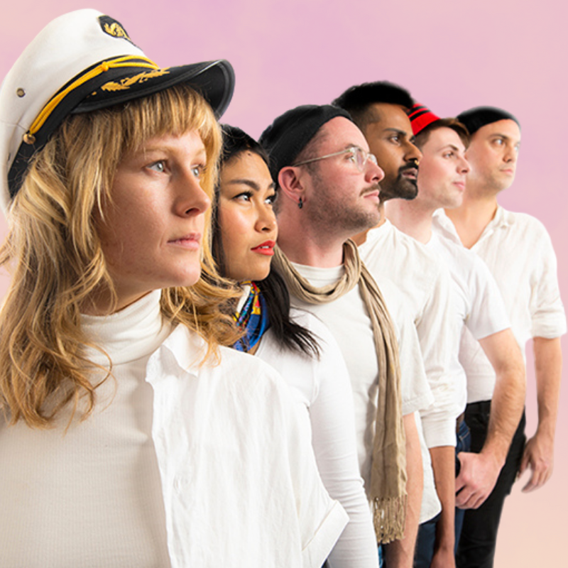Six singers against a pink sunset backdrop staring out to the distance. They are of multiple ethnicities and wearing white nautical inspired outfits which are unique to each of their personalities.