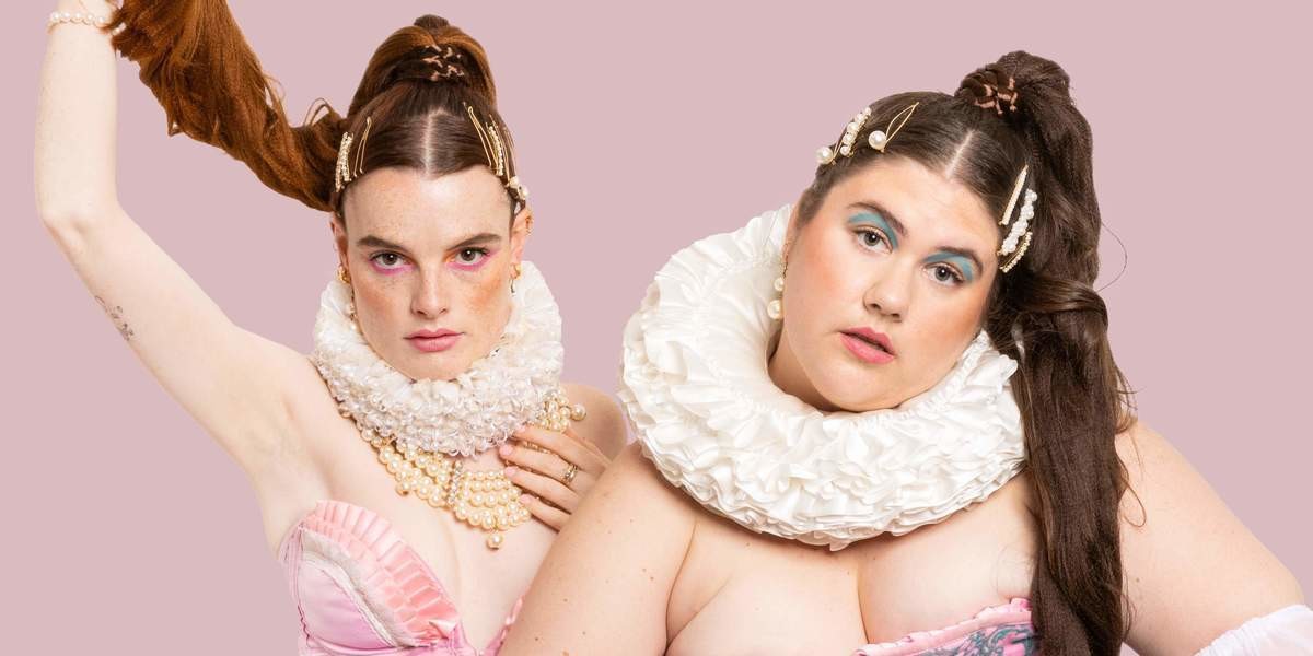 HIGH PONY - Mel & Sam smize down the barrel of the camera. They are dressed in Marie Antoinette-esque garb, with neck ruffles and opulent jewellery. They each sport a ridiculously long high pony tail on their heads and have coral and blue graphic eyeliner on.