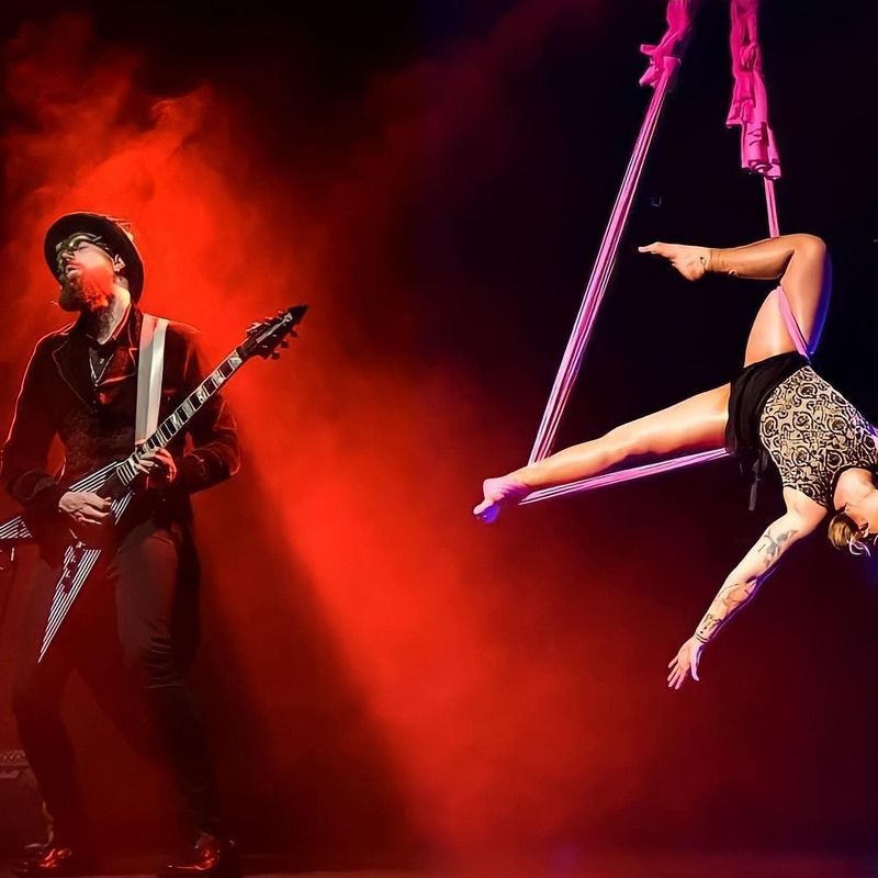 Scott Reed plays the guitar while Chantelle Reed performs on an aerial hammock next to him