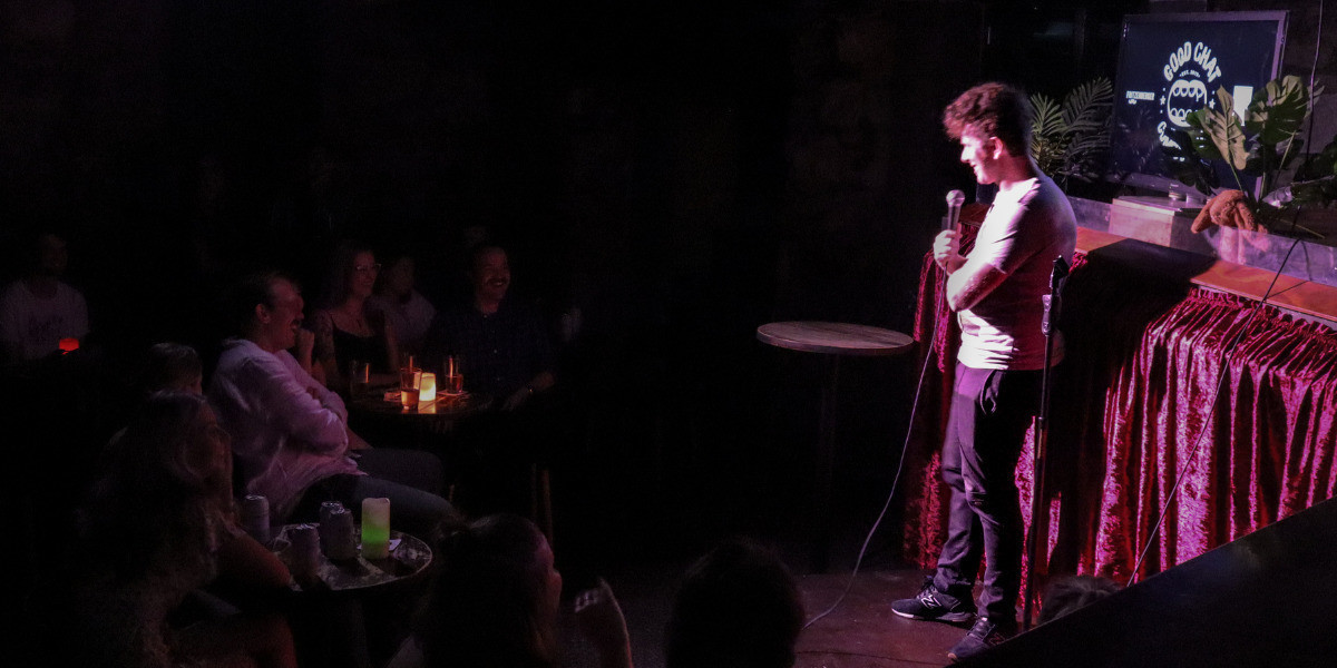 Nick Capper, on stage at Good Chat Comedy Club, engaging with the audience as part of a stand-up comedy set.