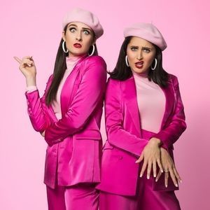 Two girls in pink suits. They both were match berets. They are striking a sassy pose and pouting their lips.