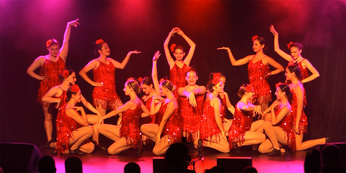 Image of dancers in red sequinned costumes holding a pose.