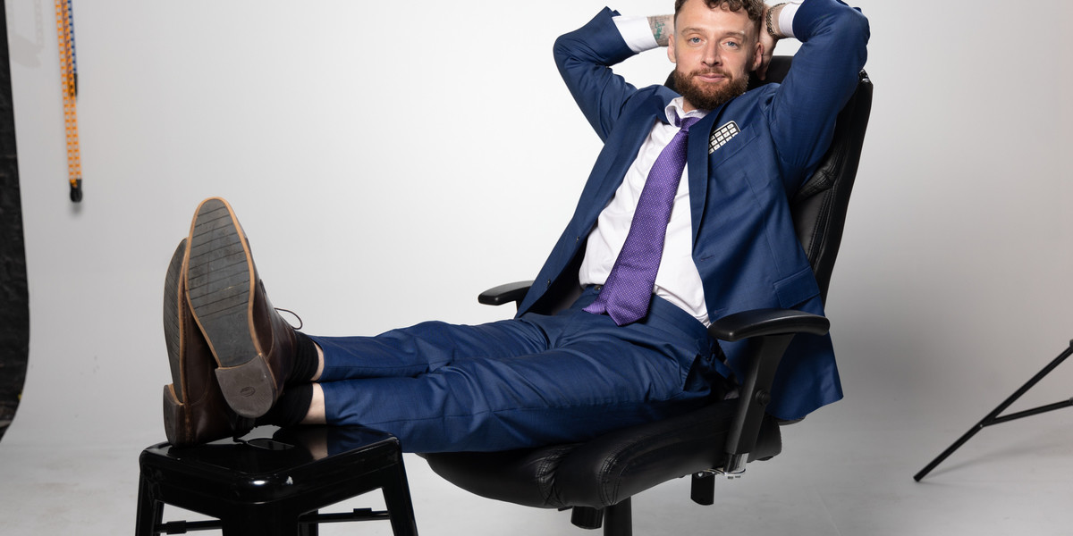 Comedian in blue suit sitting on office chair