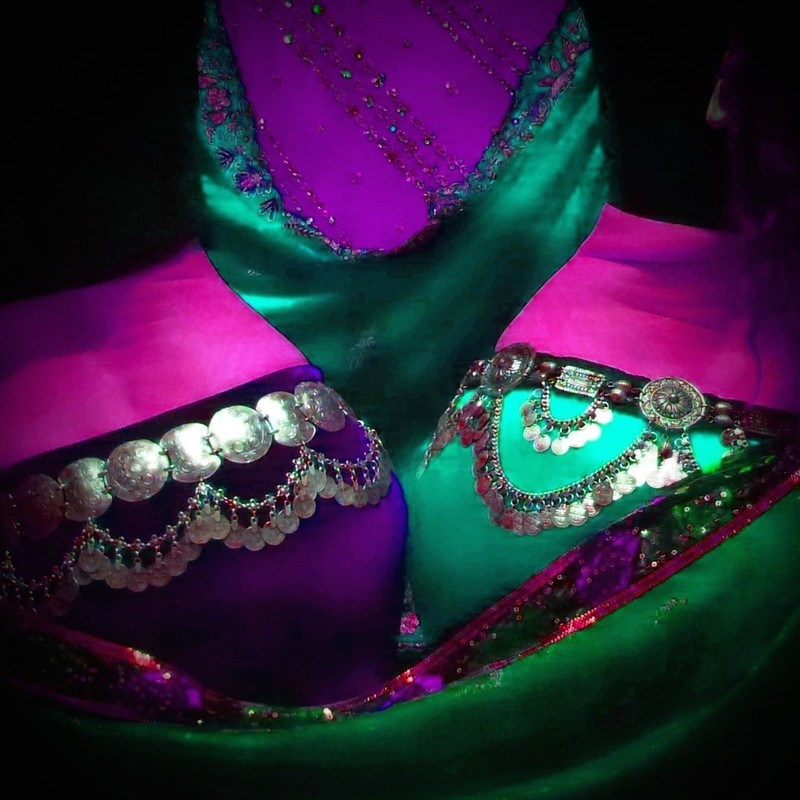 An image of a pink, purple and green silky costume which is adorned with silver embellishments.