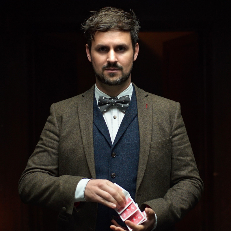 Magician Kevin Quantum springing cards from one hand to another in a dark environment