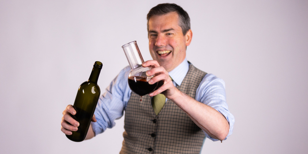 Person laughing while pouring wine into a science beaker