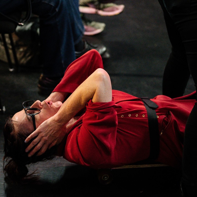 A woman with red jacket laying on her back, hands pressed to ears