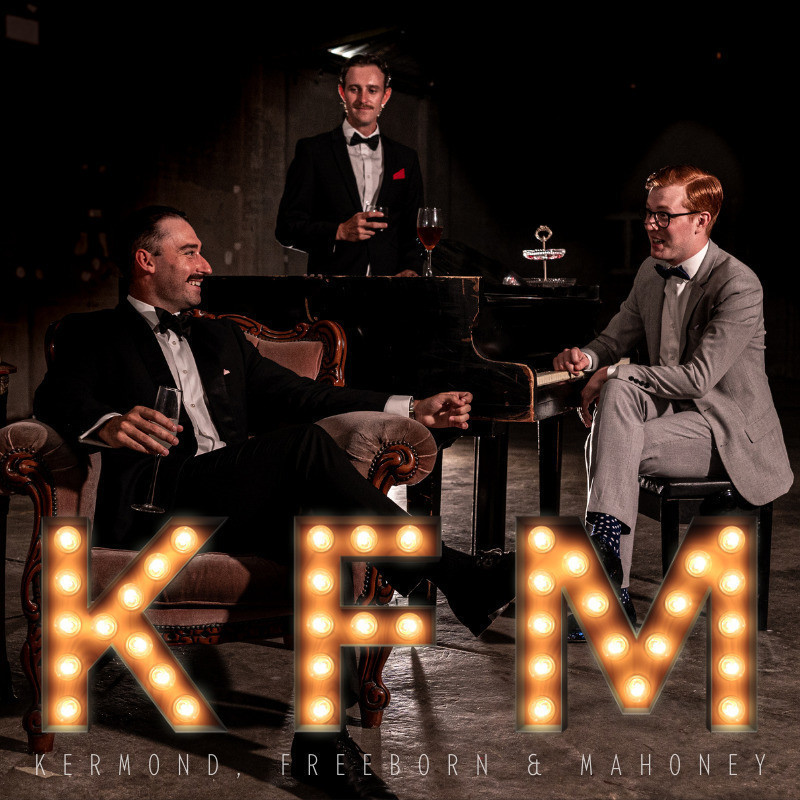 Kermond, Freeborn & Mahoney LIVE - KFM LIVE
Three cast members sharing a laugh with each other dressed in classy dinner suits around a Piano.