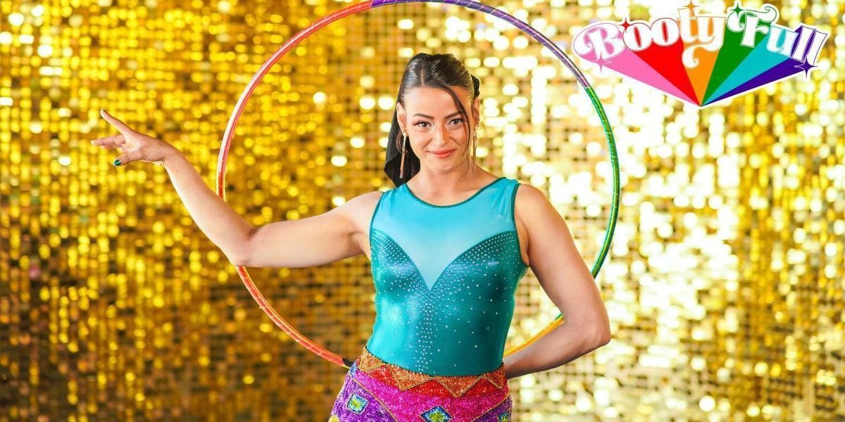 Artist in a brightly coloured leotard stands before a gold shimmery background with a hoop and the title, Booty-ful.
