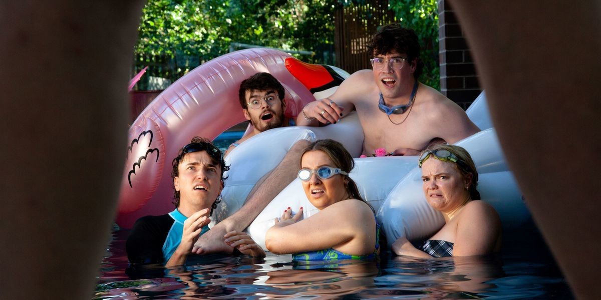Five people swimming in a pool together. They are grouped together and looking with fear toward a figure behind the camera looming over them. The edge of the looming figure's legs frames the concerned people's faces.