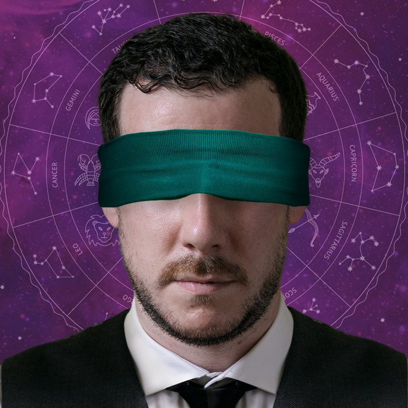 A headshot photo of a guy with a green mask covering his eyes. He has short black hair and stubble around his chin. The background is purple with white text depicting the astrological signs.