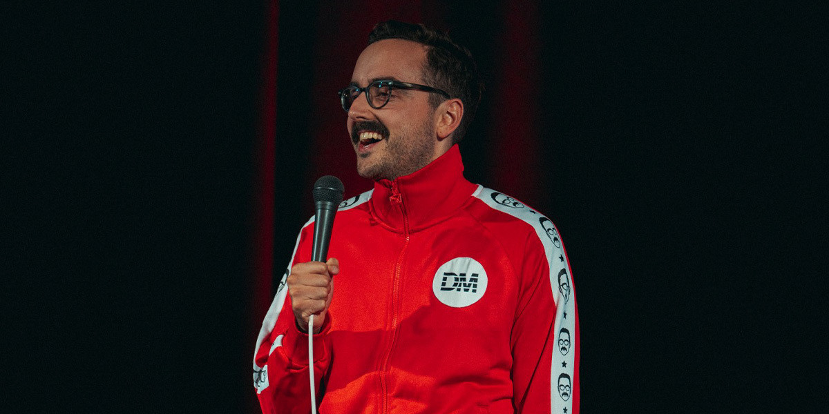Man wearing a red tracksuit is holding a microphone