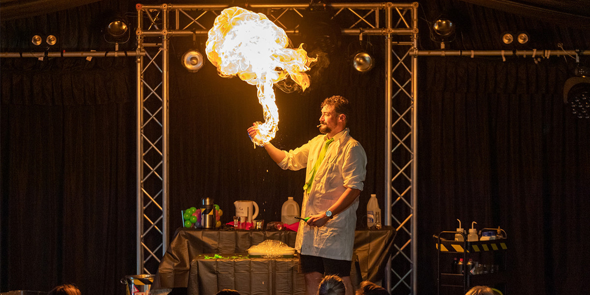 Scientist performer, live image with hand on fire and big fire ball shooting off upwards.