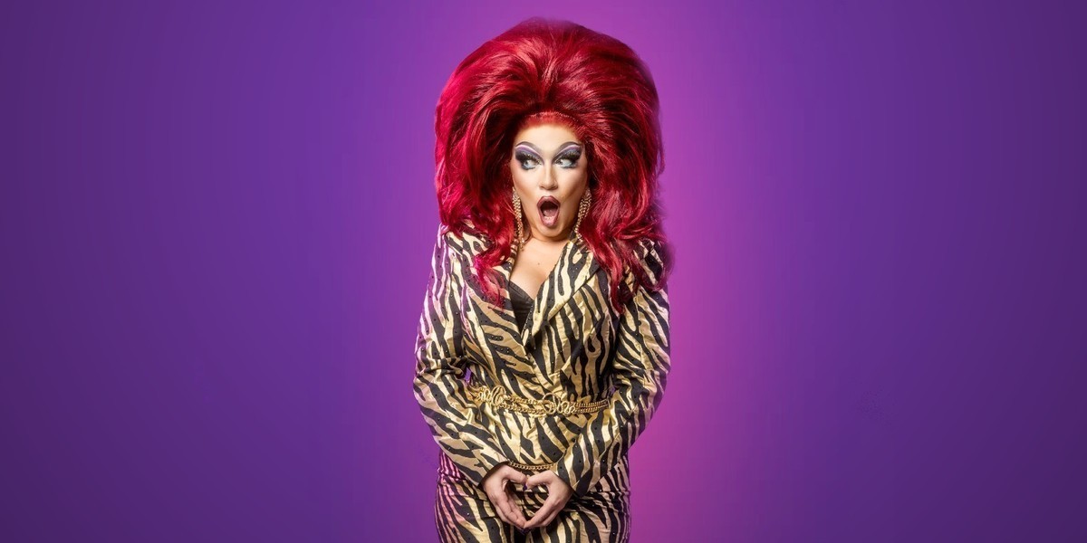 Woman in Gold jumpsuit with drag stying in front of purple background.