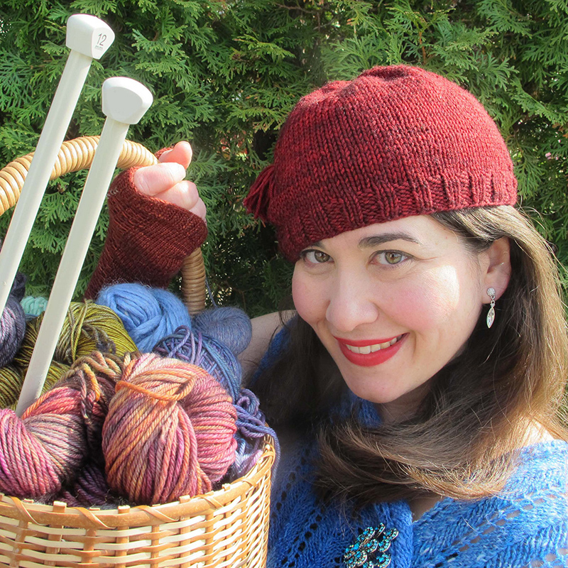 Brunette wearing a knitted outfit and holding knitting needles.