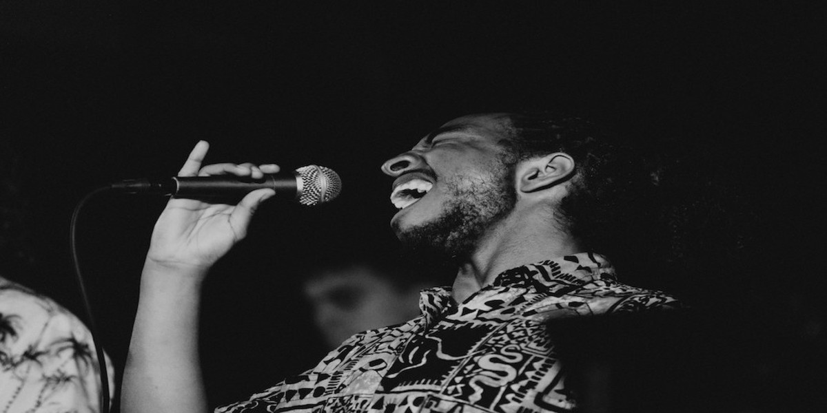 Man singing with a wide open mouth and eyes closed.