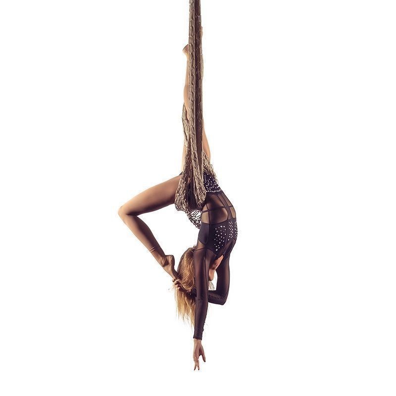 Aerial Performer in a black studded leotard hanging upside down by aerial netting