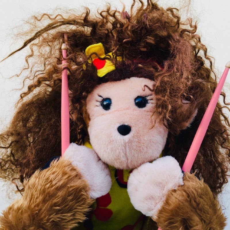 Kiiko the girl monkey puppet holding her pink drum sticks.