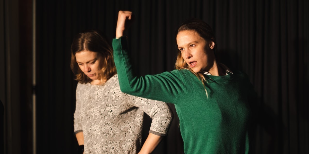 Two women are performing on stage, with confident, powerful postures