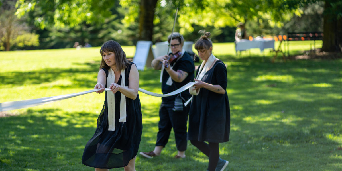 three performers including a dancer and a musician in the botanic gardens