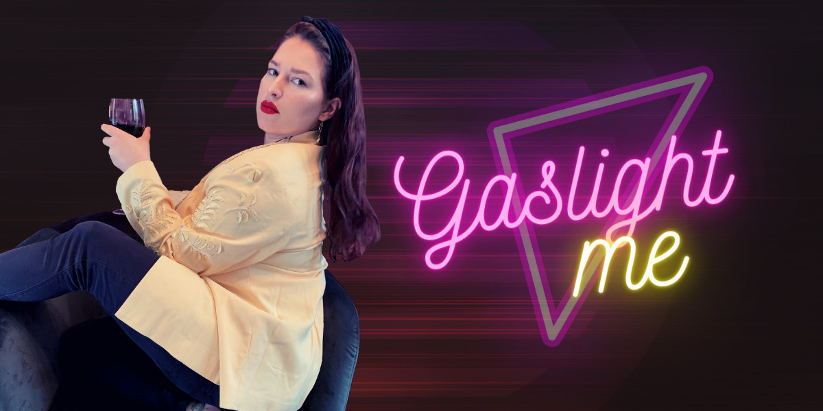 Gaslight Me - Woman sits sideways on a velvet chair. She is wearing a yellow blazer, her long hair falling down her back. She is holding a glass of red wine and looking directly at the viewer. Title on the left of her says Gaslight Me in neon writing.