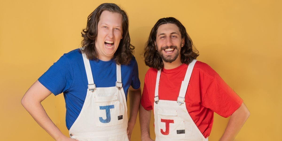 Jon and Jero standing together in front of a yellow backdrop.