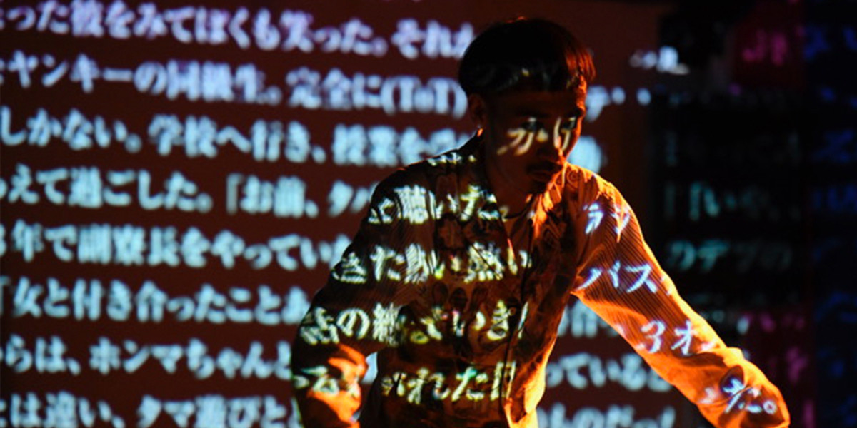 Projection of Japanese characters with a man in front of it.
