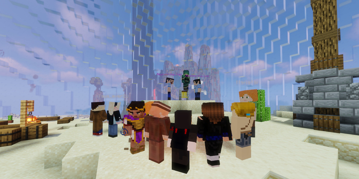 A screenshot from the video game Minecraft depicts a group of 11 players huddled together in a circle. It is daytime and they are on a sandy hill inside a huge glass dome. Outside the dome, large cliffs and a tall tower can be seen extending above the top of the frame.