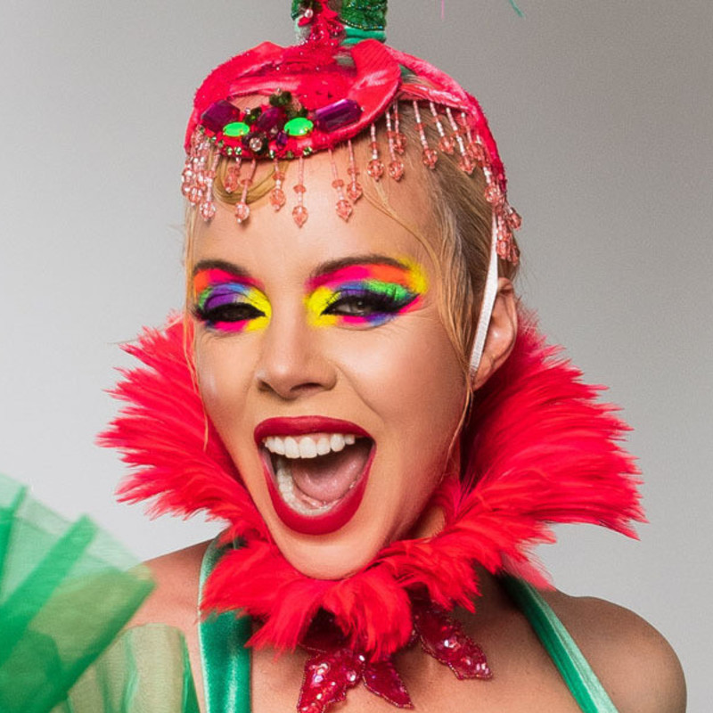 Photo by Joel Devereux of Imogen Kelly in green and pink headdress and a huge smile!