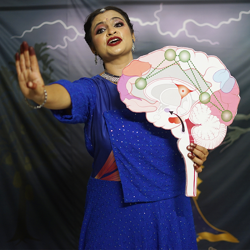 A young lady dressed in blue holds an image of a medical diagram of a brain in her left hand, while her right hand is extended outwards as if to ward something off. In the backdrop are grey skies with a stroke of lightning.