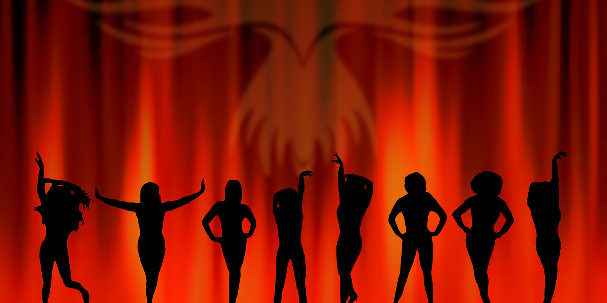 Silhouette of 8 women against a background of flames, with an image of a phoenix rising in the background.