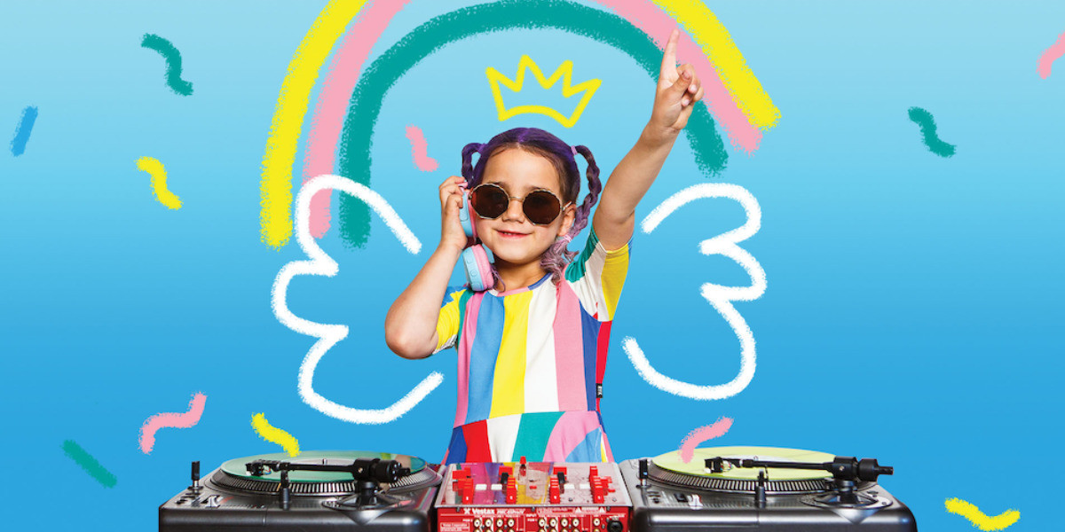 DJ Alba Lorca stands at the decks holding her finger in the air and headphones to her ear,