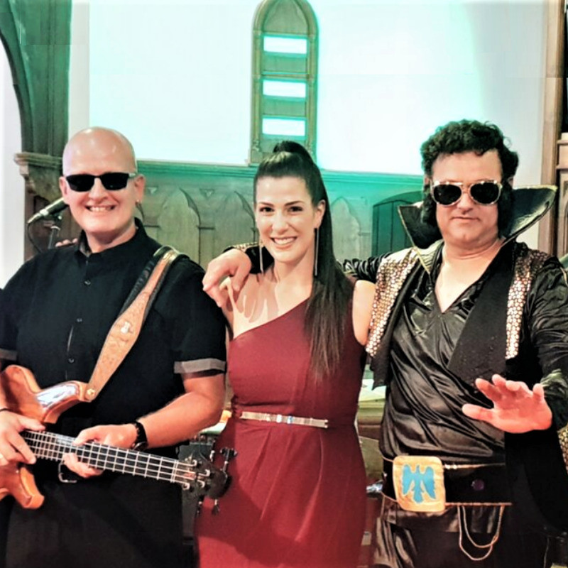3 members of the sensational band.  they are dressed up in costumes. The lead lady singer as a rock and roll person.    the guy on the left with guitar part of the rock and roll theme.  Far right of this picture is Tony dressed up as Elvis.